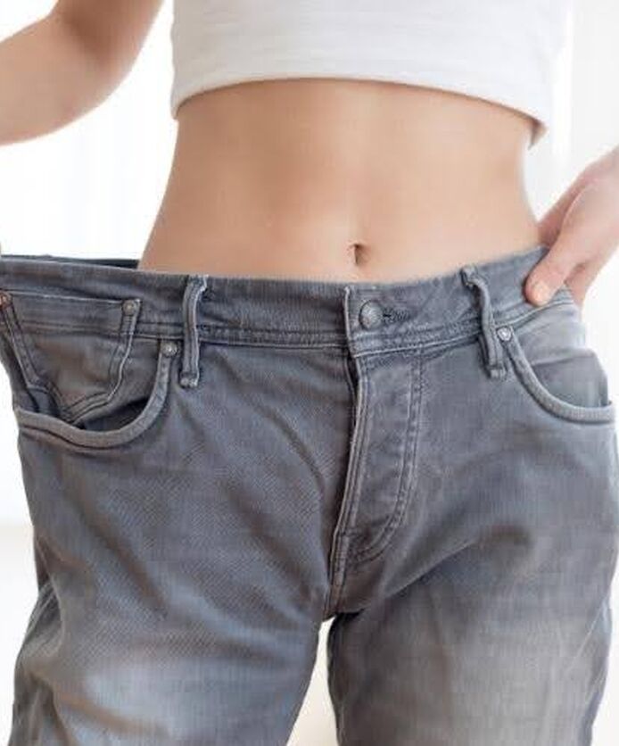 Weight loss progress with loose fitting jeans on waist.